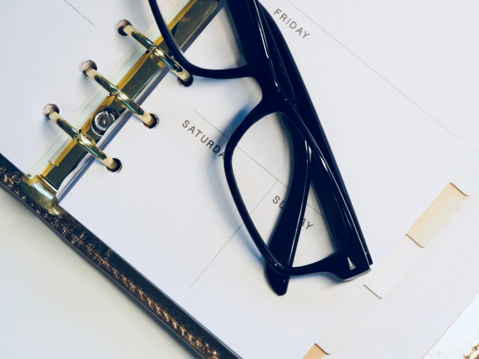 Aufgeschlagener Ringkalender mit Brille auf der Seite des Wochenendes