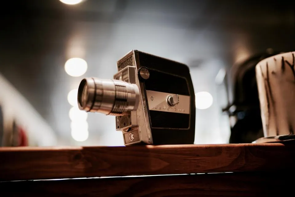 Vintage-Filmkamera auf einem Holzregal mit unscharfen Lichtern im Hintergrund