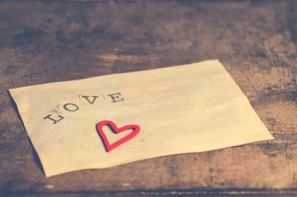 Briefumschlag mit dem Wort LOVE und einem Herz auf Holz
