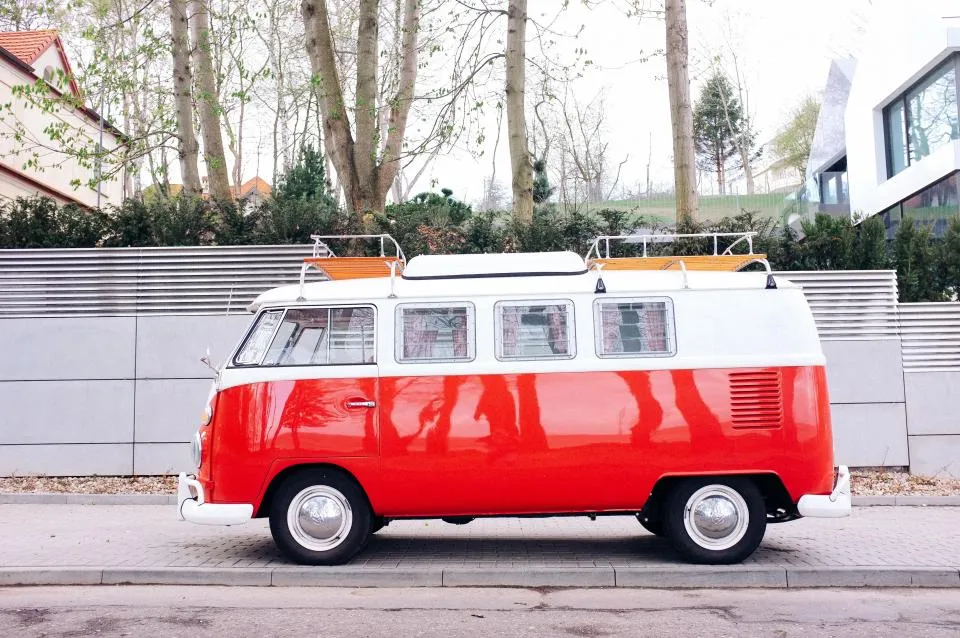 Autobus d'epoca rosso e bianco parcheggiato lungo una strada alberata