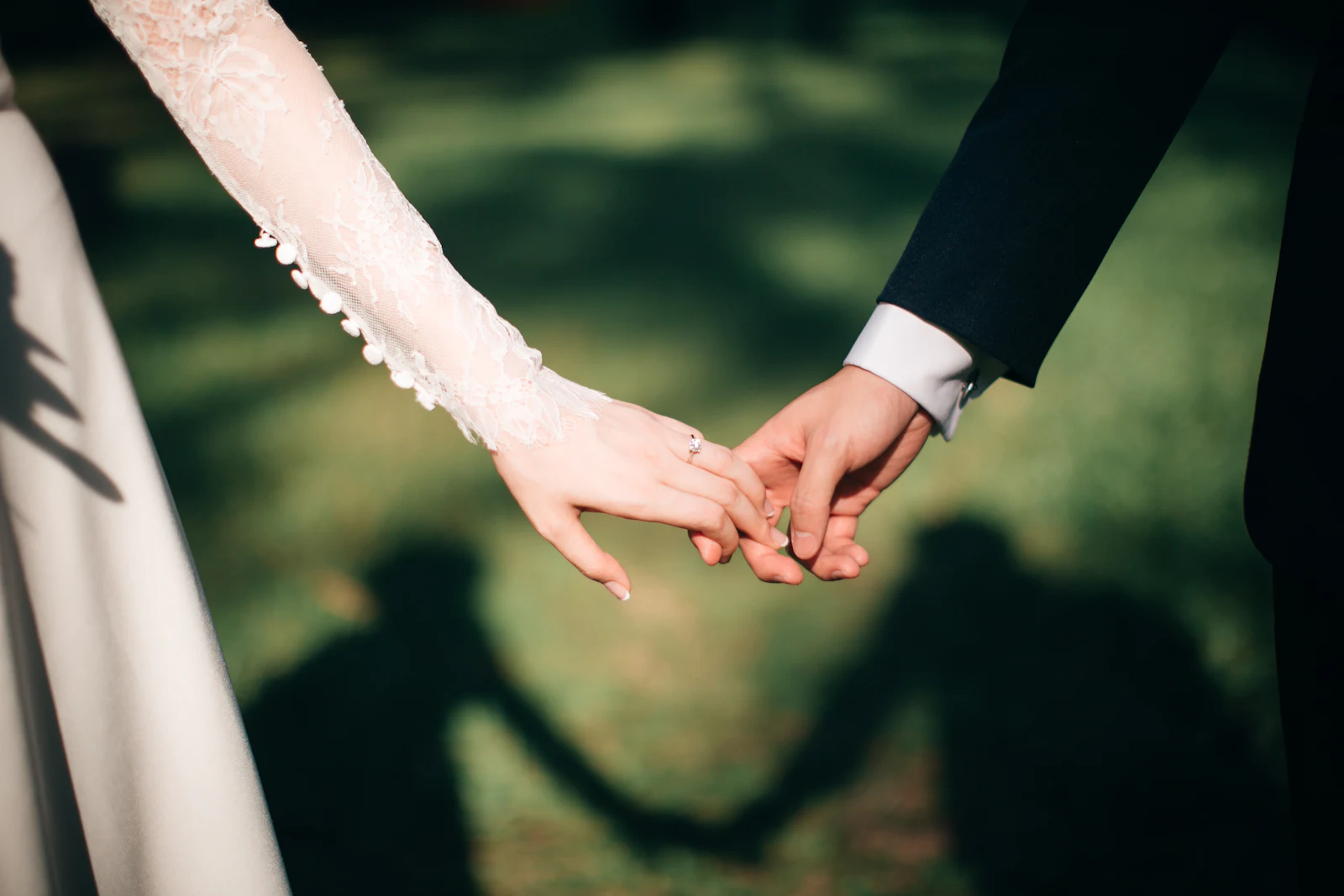 Primer plano de los novios cogidos de la mano el día de su boda
